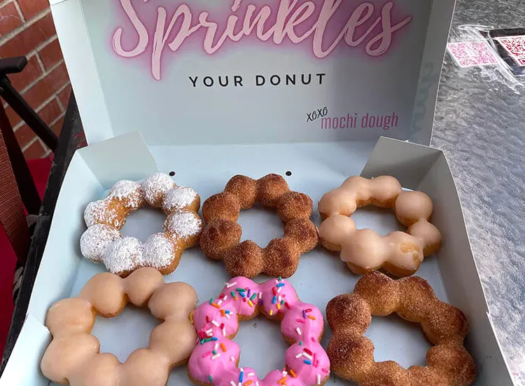 6 donas de mochi diferentes en una caja que dice: Sprinkles your donut. XOXO Mochi Dough.
