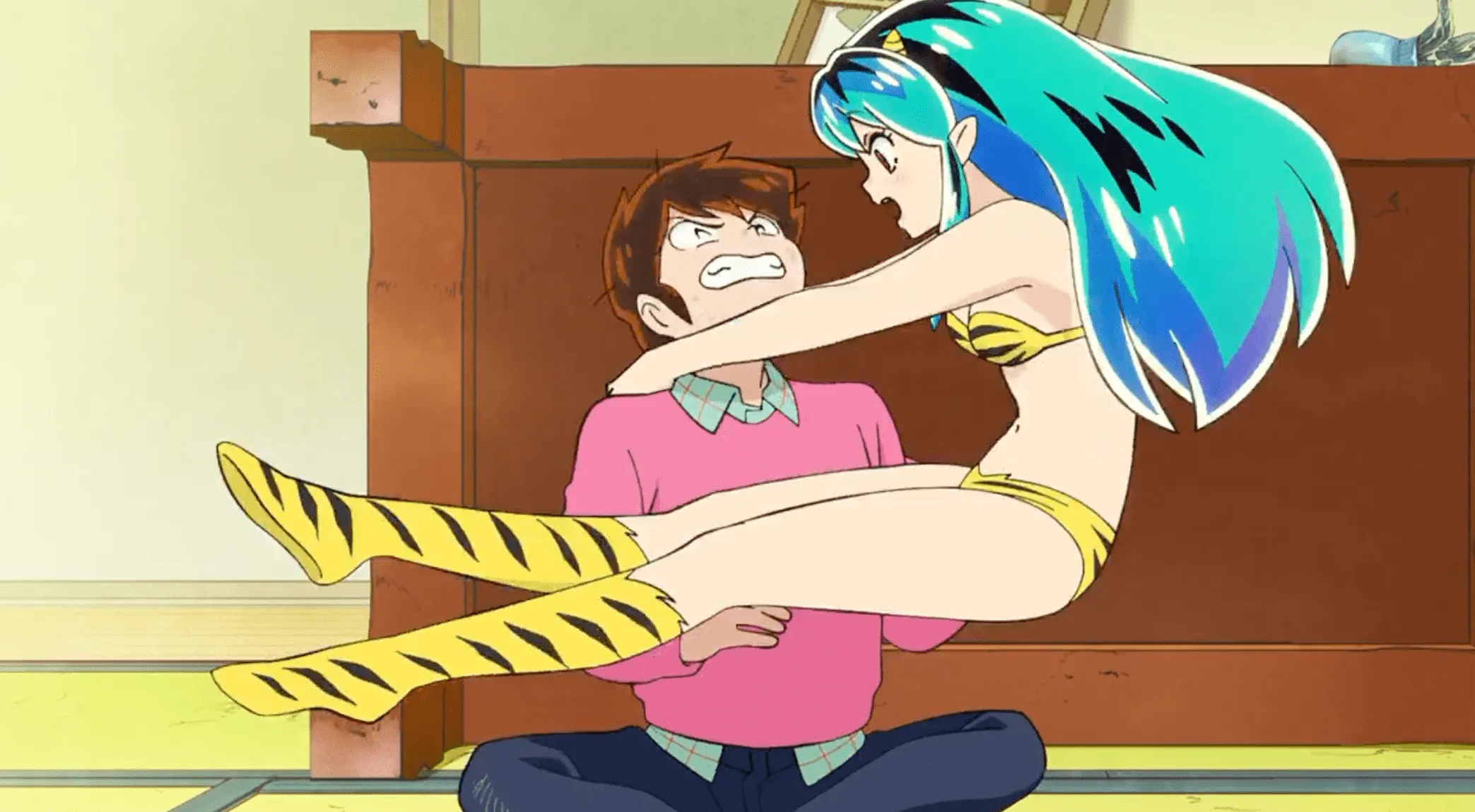 Lum flotando sobre el regazo de Ataru, tratando de sujetarlo mientras él frunce el ceño cómicamente.